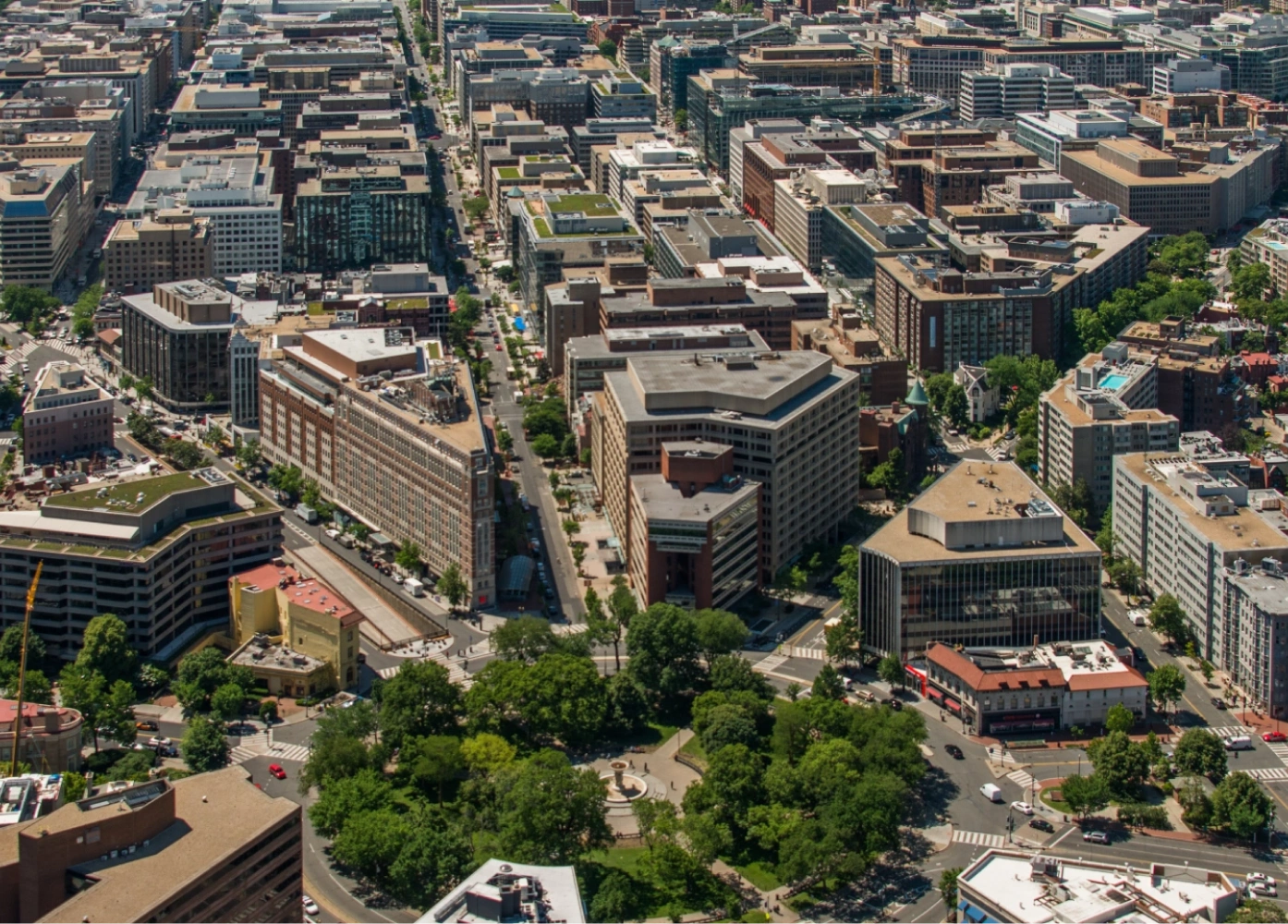 Dupont Circle in Washington DC with office buildings, tree-lined streets, & the central park fountain